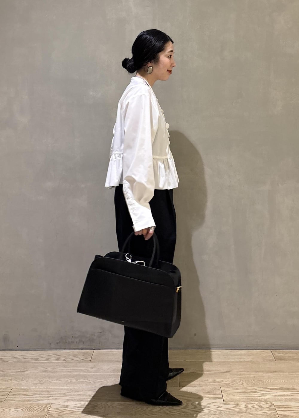 ホワイト系のシャツ/ブラウス、ブラック系のスラックス、ブラック系のトートバッグを着用したレディースの冬コーディネートの3枚目の写真