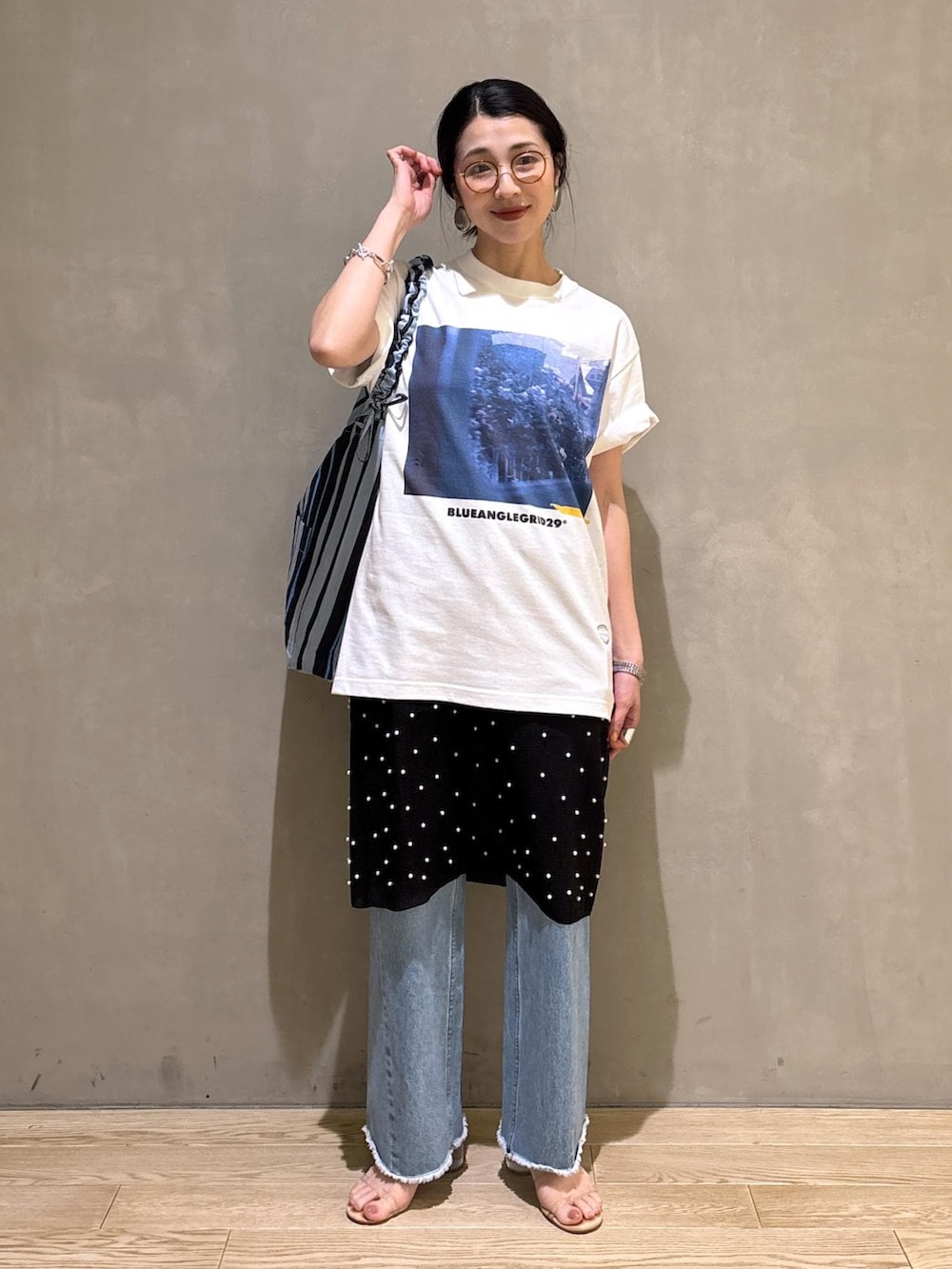 ブルー系のデニムパンツ、ブルー系のショルダーバッグ、ホワイト系のTシャツ/カットソーを着用したレディースの春コーディネートの3枚目の写真