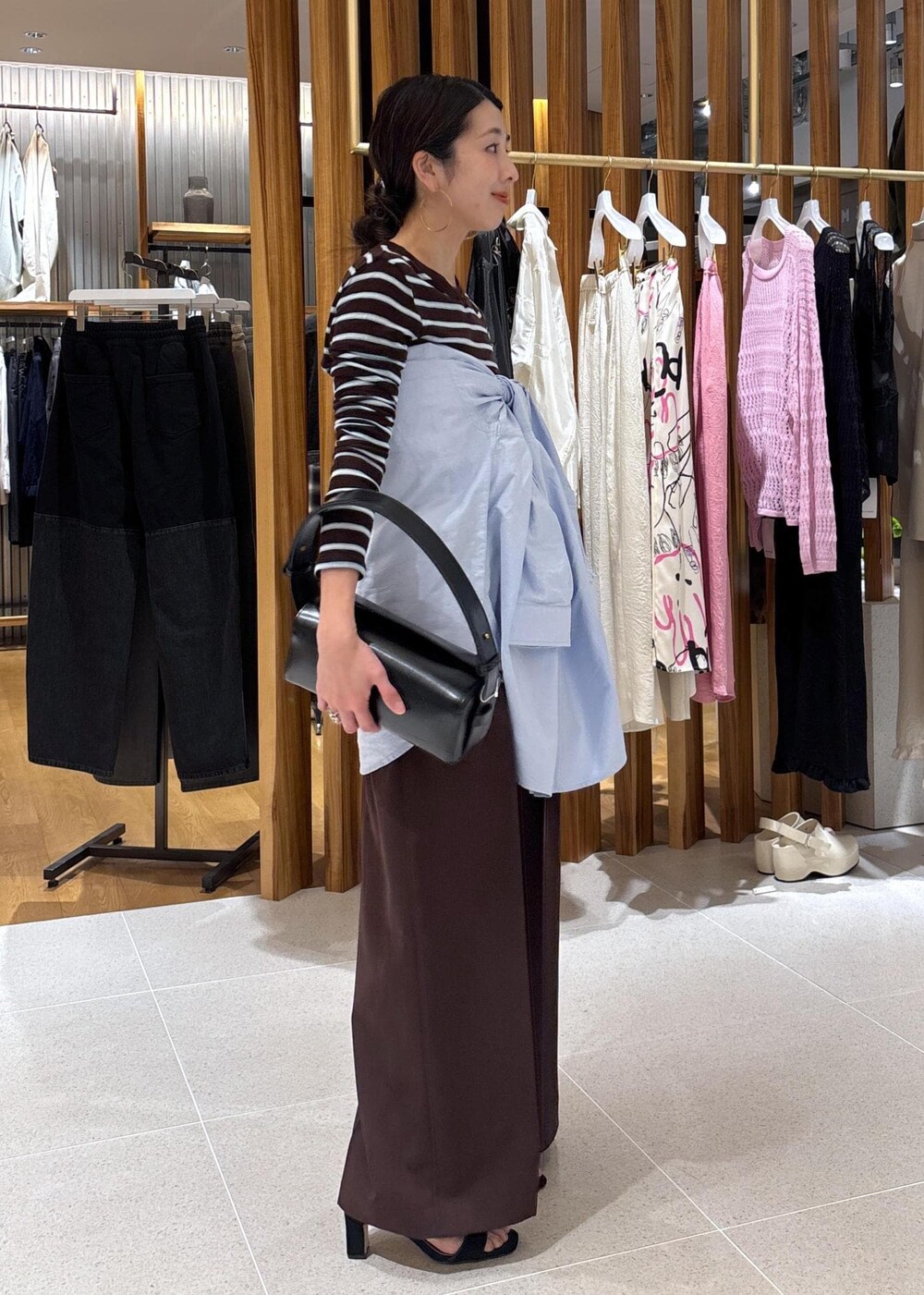 ブラック系のハンドバッグ、ブルー系のシャツ/ブラウス、ブラウン系のTシャツ/カットソーを着用したレディースの春コーディネートの4枚目の写真