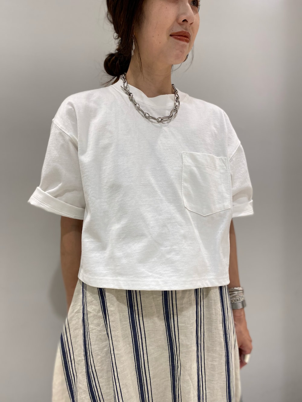 ベージュ系のワンピース、ホワイト系のTシャツ/カットソー、シルバー系のネックレスを着用したレディースの春コーディネートの3枚目の写真