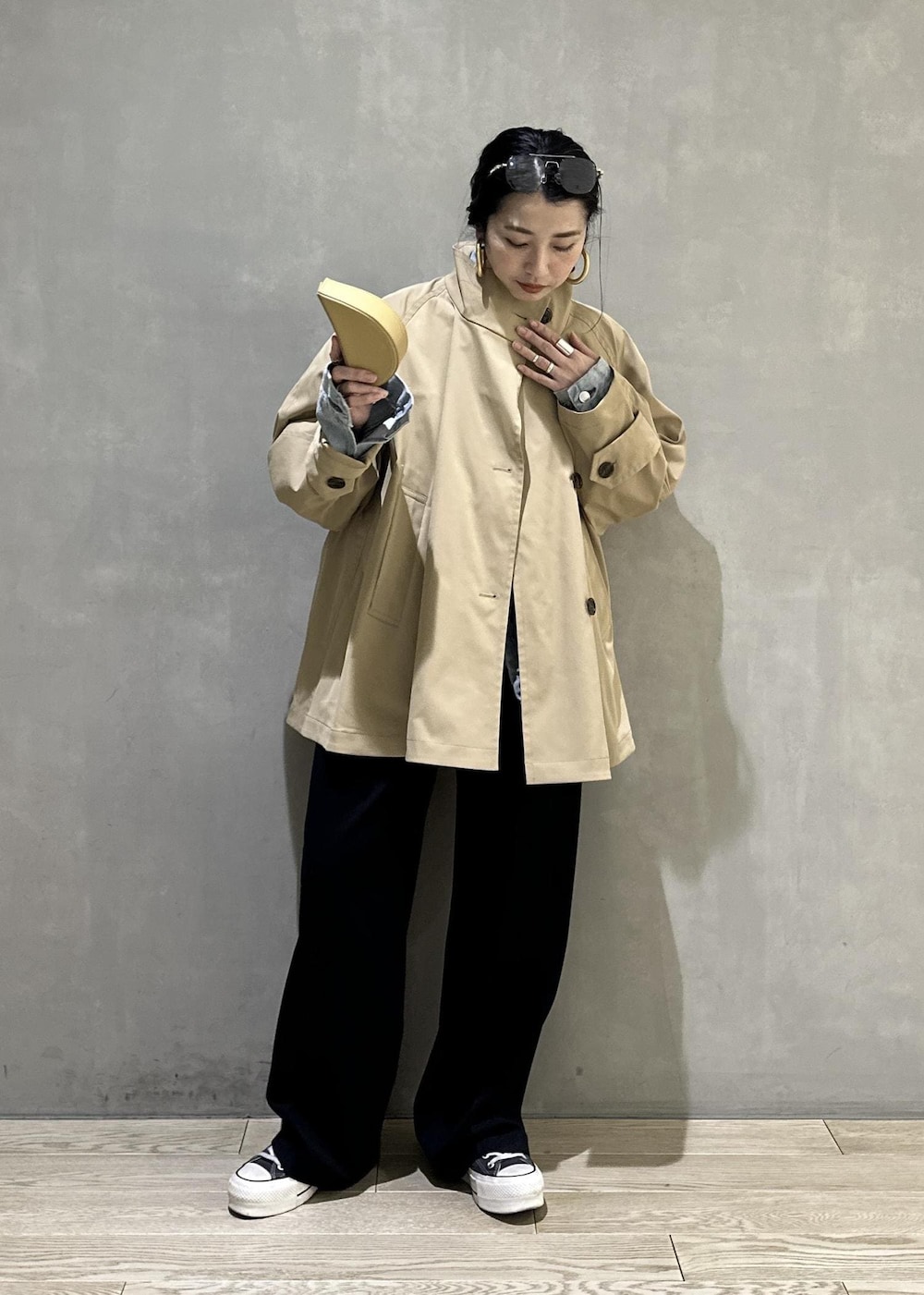 ベージュ系のトレンチコート、ブラック系のスラックス、イエロー系のキーホルダーを着用したレディースの冬コーディネートの2枚目の写真