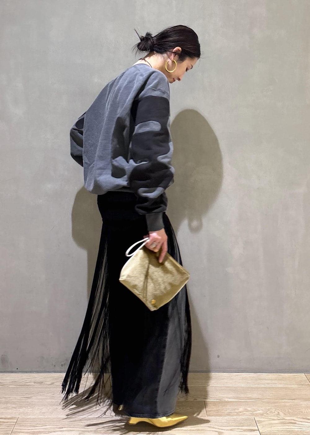 ブラック系のデニムパンツ、ブラック系のスカート、ベージュ系のポーチを着用したレディースの冬コーディネートの5枚目の写真