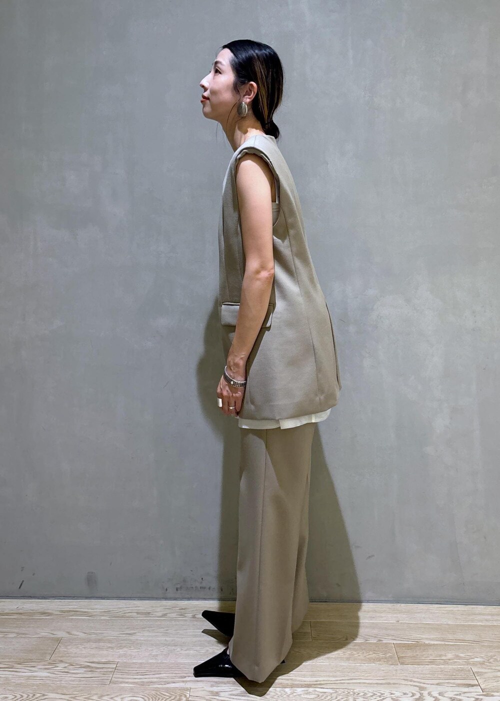 ブラック系のパンプス、ベージュ系のベスト、ベージュ系のスラックスを着用したレディースの夏コーディネートの6枚目の写真