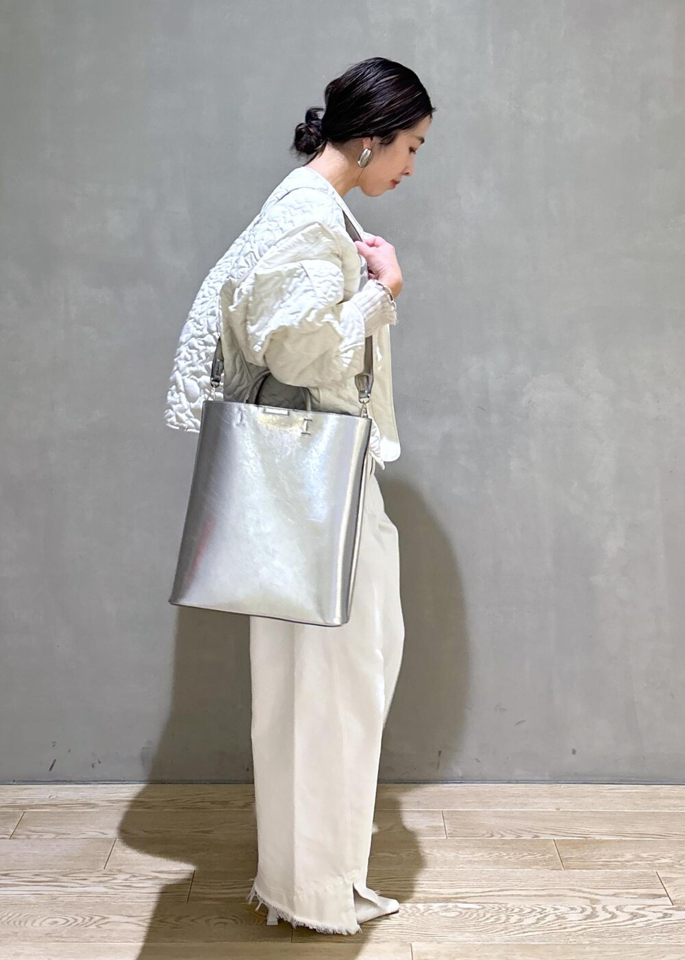ホワイト系のパンプス、シルバー系のトートバッグ、ホワイト系のデニムパンツを着用したレディースの冬コーディネートの5枚目の写真