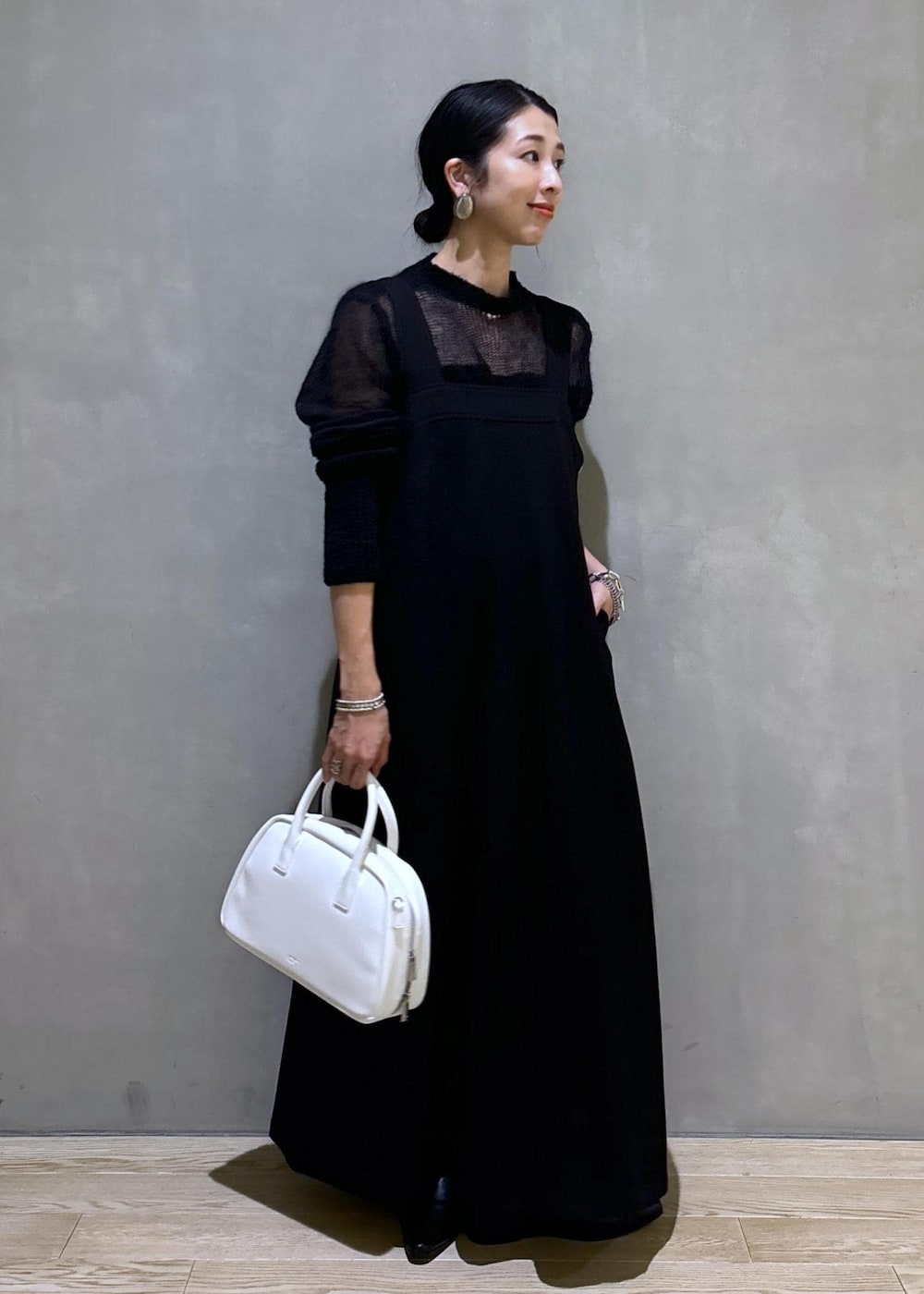 ホワイト系のボストンバッグ、ブラック系のワンピース、ブラック系のブーツを着用したレディースの秋コーディネートの3枚目の写真