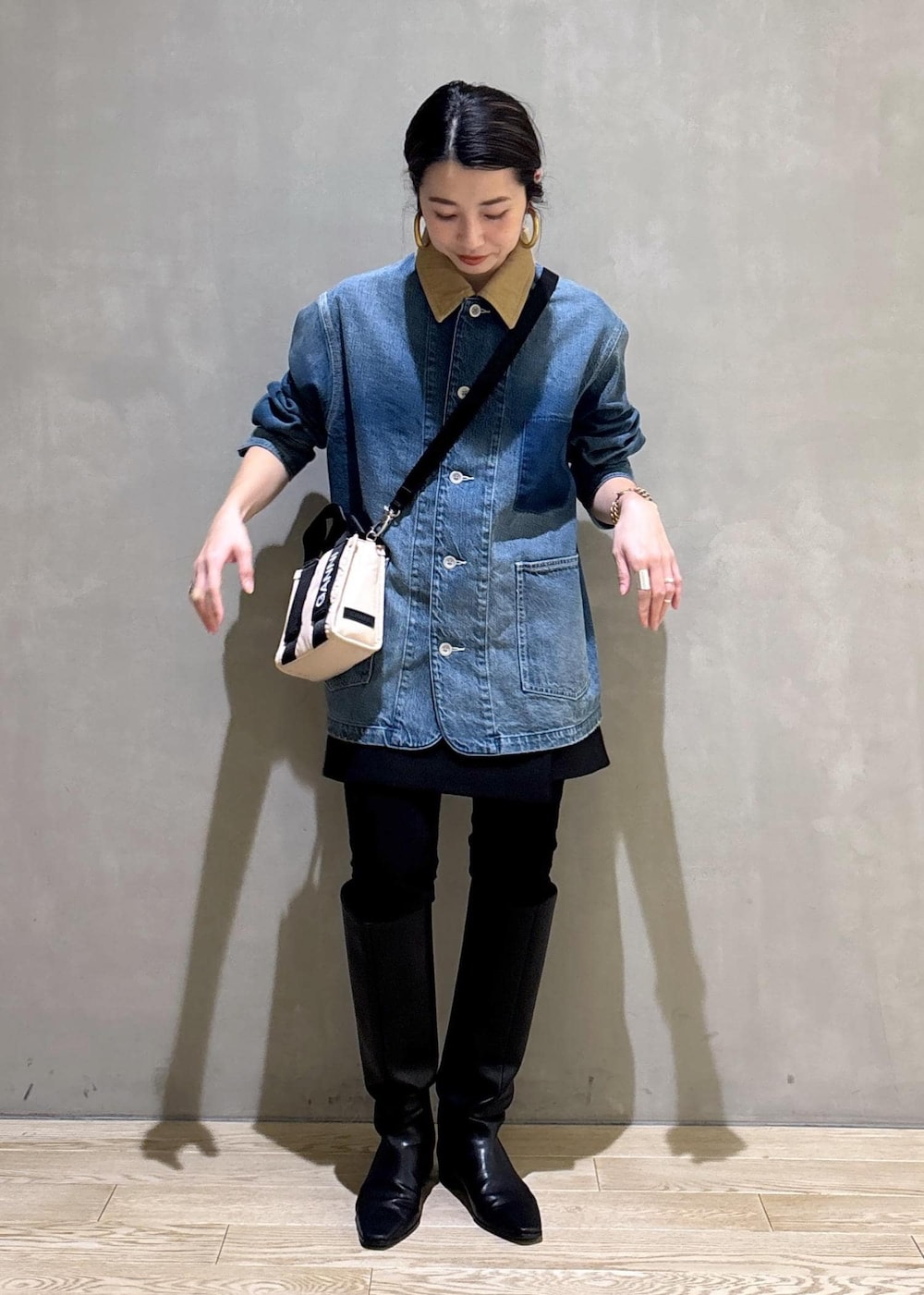 ベージュ系のトートバッグ、ブラック系のブーツ、ブラック系のスカートを着用したレディースの冬コーディネートの2枚目の写真