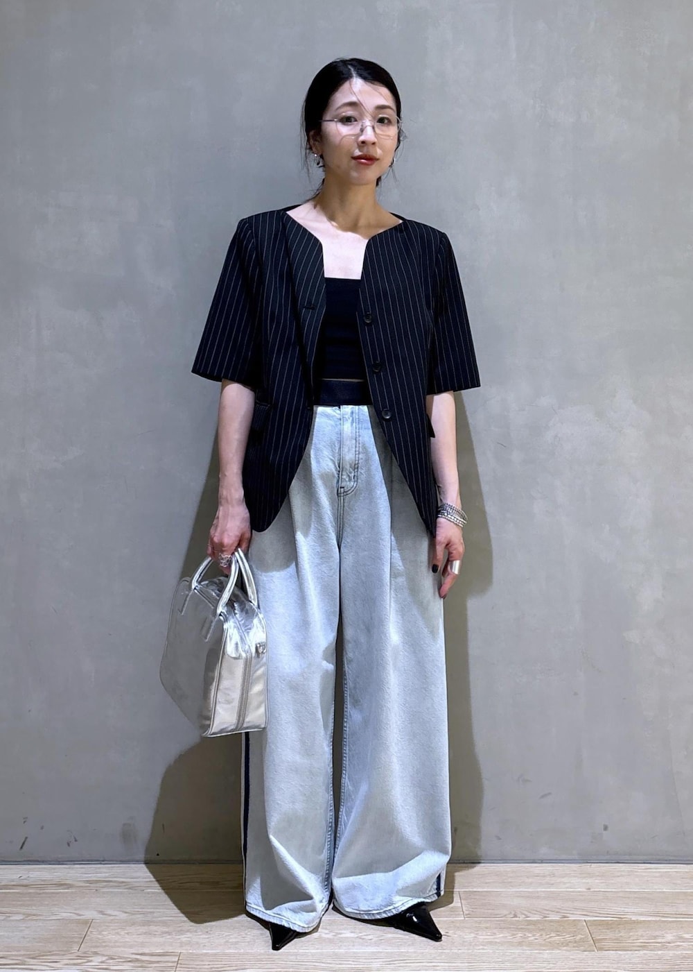 ブルー系のデニムパンツ、ブラック系のノーカラージャケット、シルバー系のボストンバッグを着用したレディースの春コーディネートの3枚目の写真
