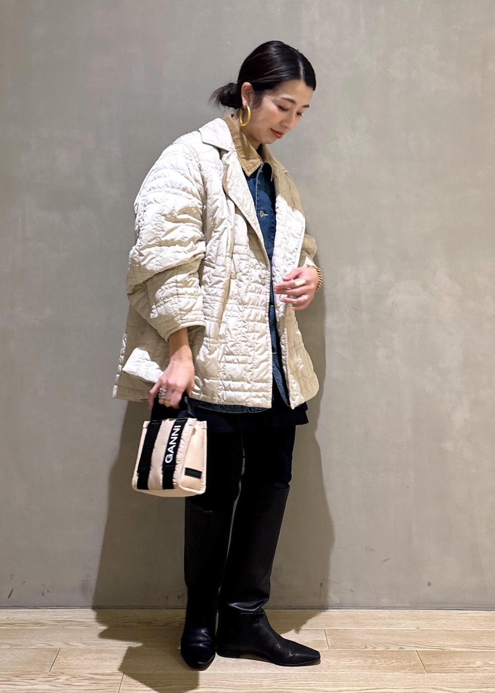 ベージュ系のトートバッグ、ブラック系のブーツ、ブラック系のスカートを着用したレディースの冬コーディネートの3枚目の写真