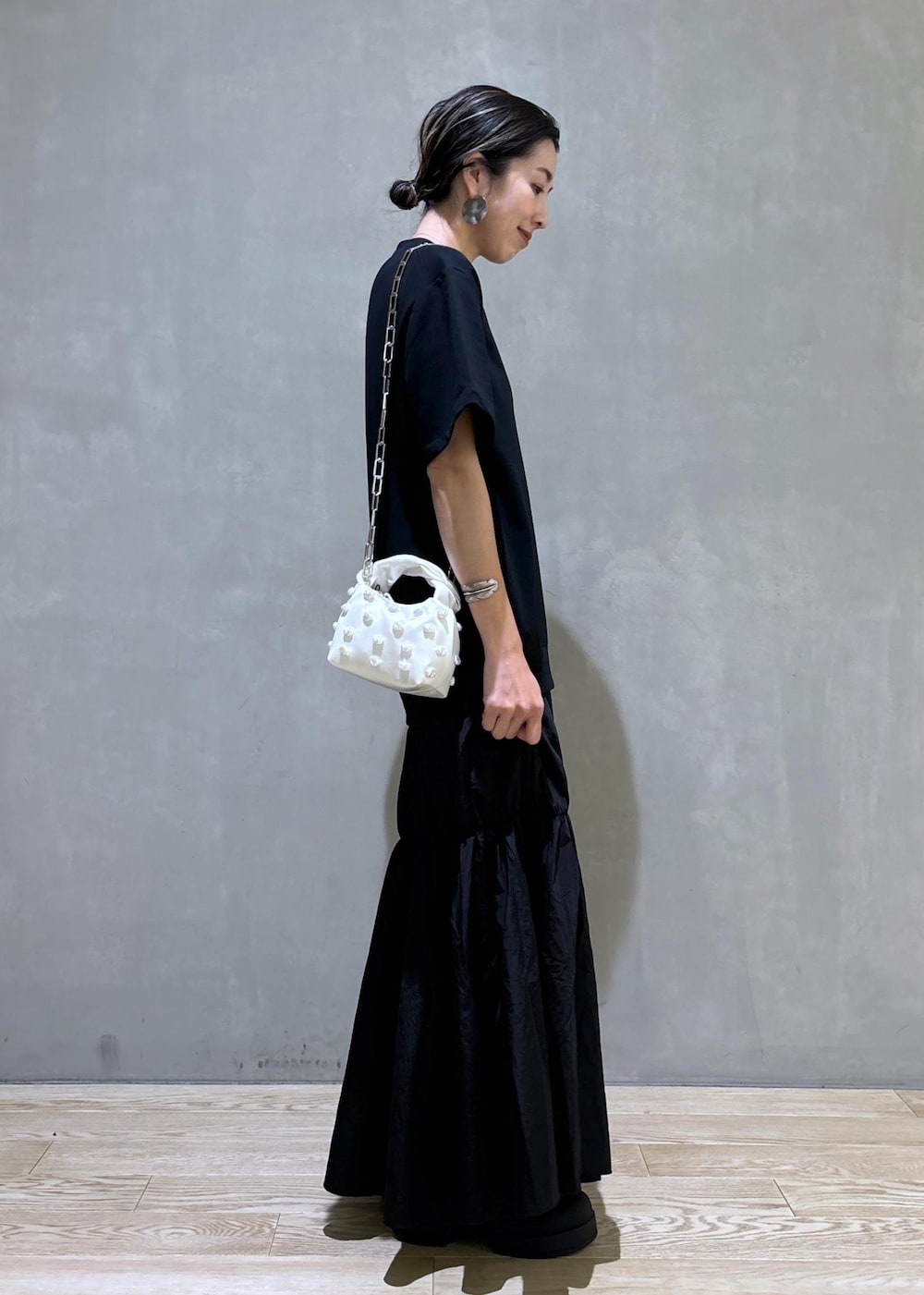 ホワイト系のショルダーバッグ、ブラック系のブーツ、ブラック系のワンピースを着用したレディースの夏コーディネートの6枚目の写真