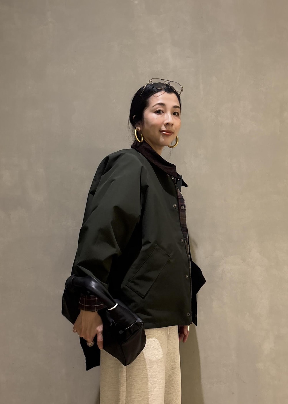 ブラック系のハンドバッグ、グリーン系のその他アウター、ホワイト系のその他パンツを着用したレディースの冬コーディネートの10枚目の写真