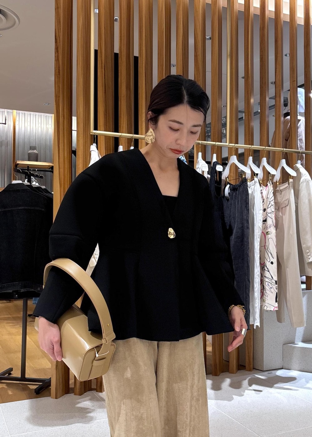ベージュ系のハンドバッグ、ブラック系のローファー、ブラック系のカーディガン/ボレロを着用したレディースの冬コーディネートの9枚目の写真