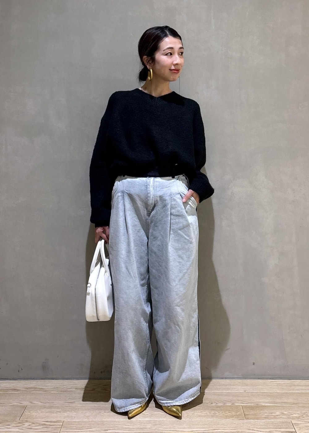 ブラック系のニット/セーター、ホワイト系のボストンバッグ、ブルー系のその他パンツを着用したレディースの冬コーディネートの3枚目の写真