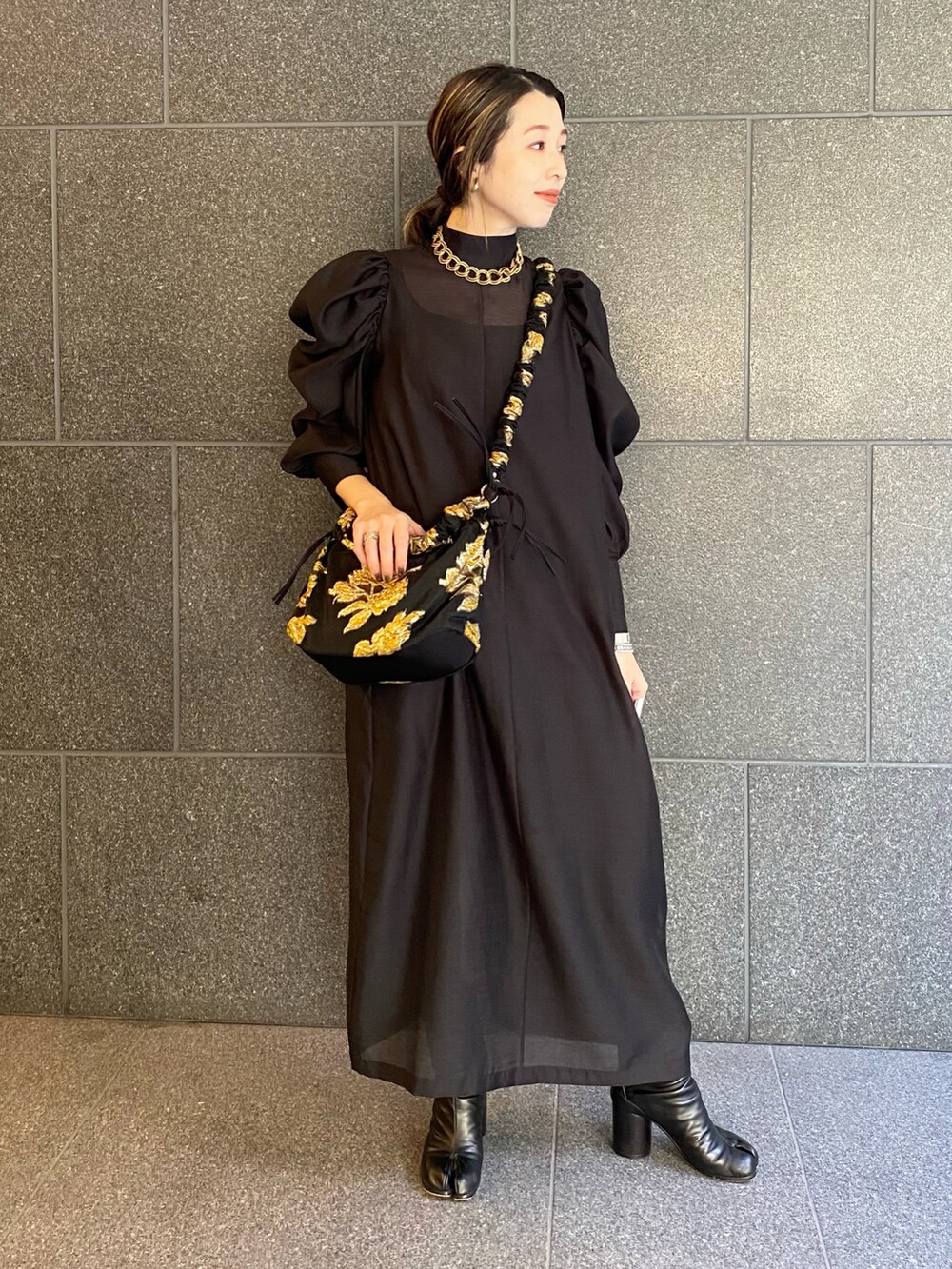 ブラック系のブーツ、ブラック系のワンピース、ブラック系のバッグを着用したレディースの春コーディネートの2枚目の写真