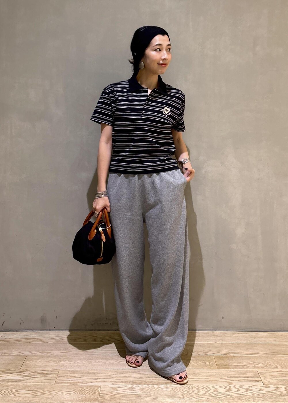 グレー系のスウェットパンツ、ブラック系のポロシャツを着用したレディースの夏コーディネートの4枚目の写真