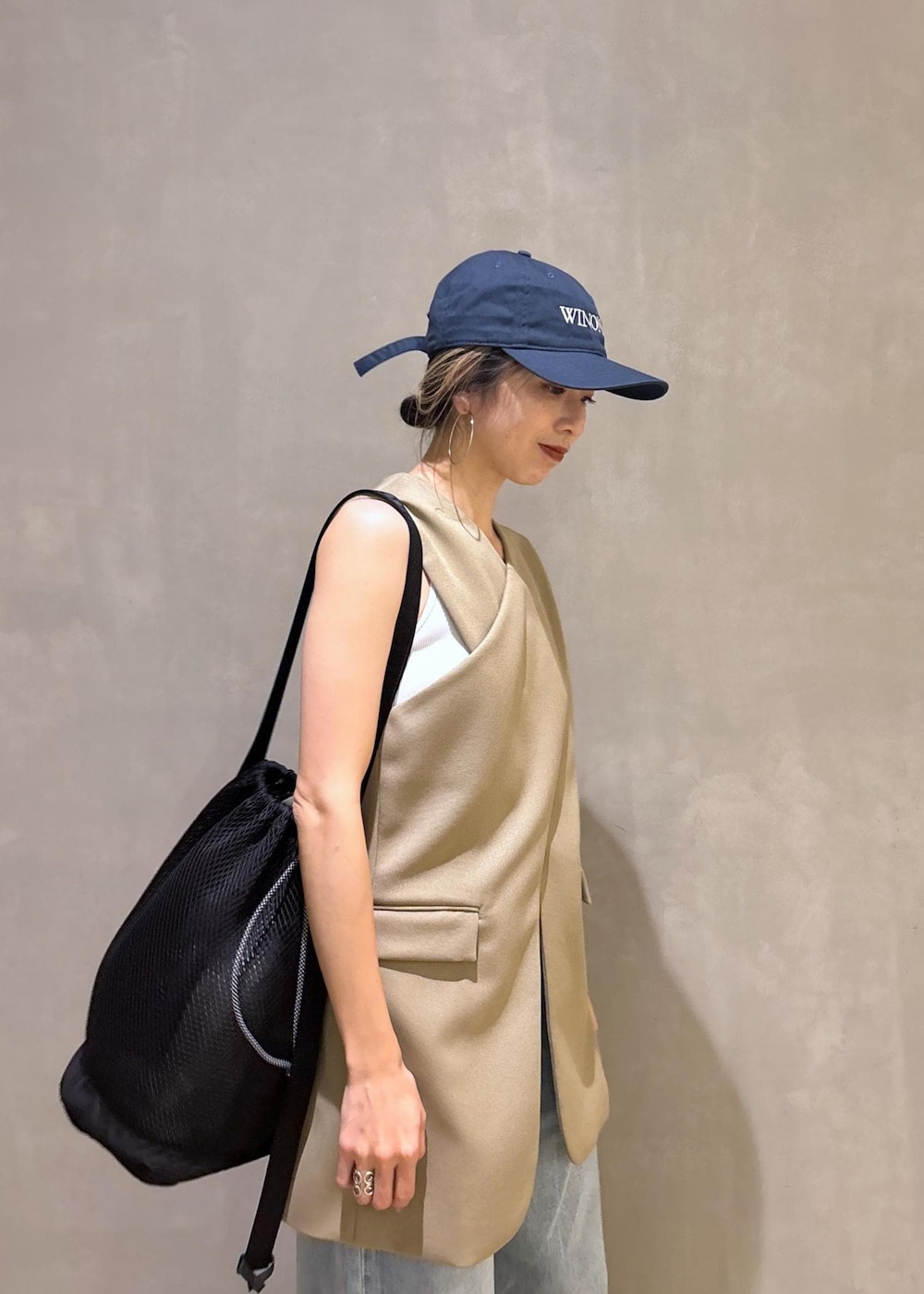 ベージュ系のベスト、ブラック系のスニーカー、ブラック系のショルダーバッグを着用したレディースの夏コーディネートの7枚目の写真