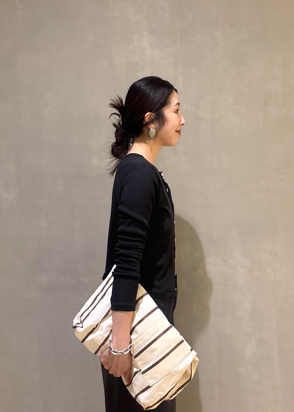 ブラック系のカーディガン/ボレロ、ホワイト系のショルダーバッグ、ブラック系のデニムパンツを着用したレディースの春コーディネートの7枚目の写真