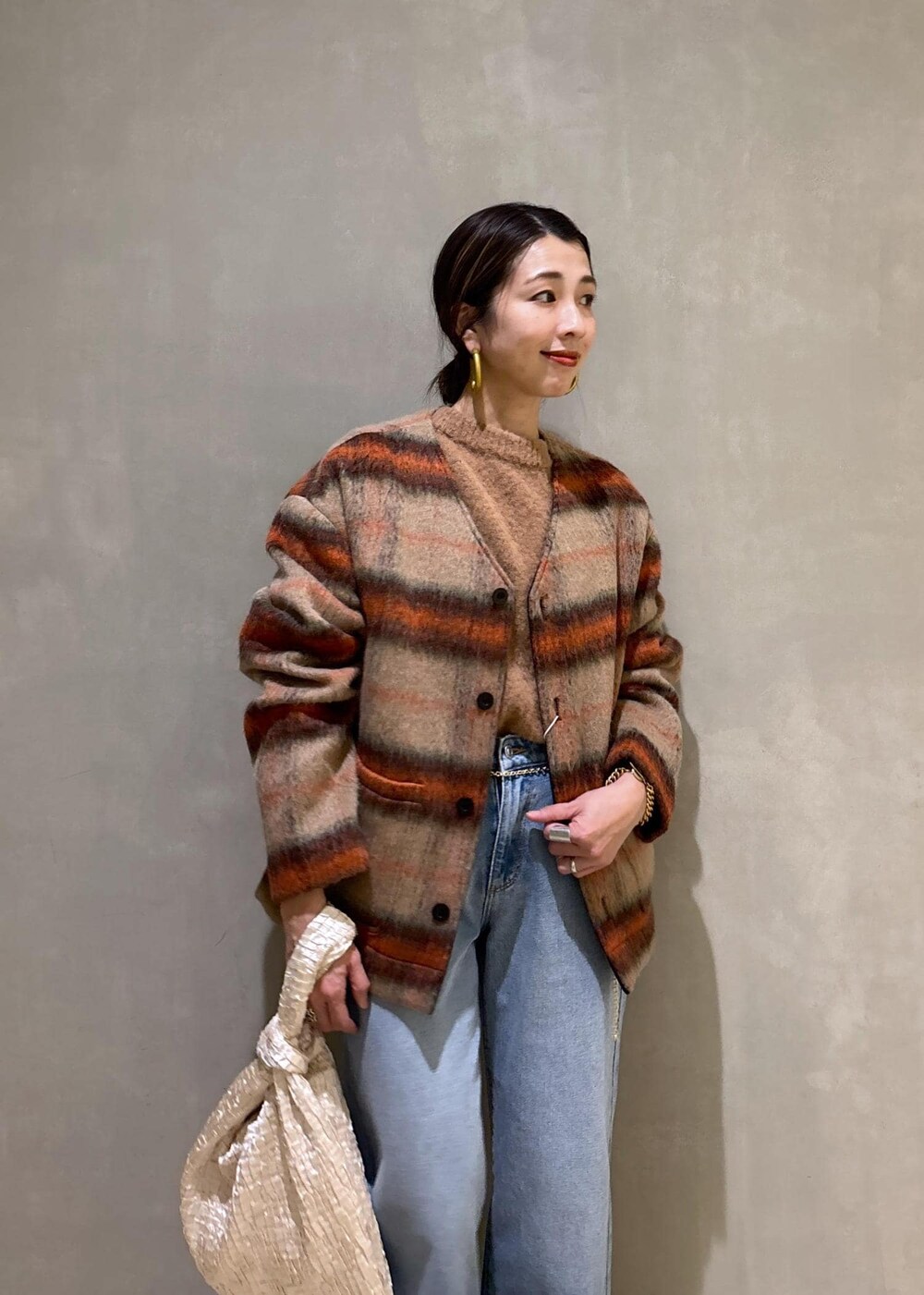 ホワイト系のハンドバッグ、ゴールド系のショルダーバッグ、ブルー系のデニムパンツを着用したレディースの冬コーディネートの9枚目の写真