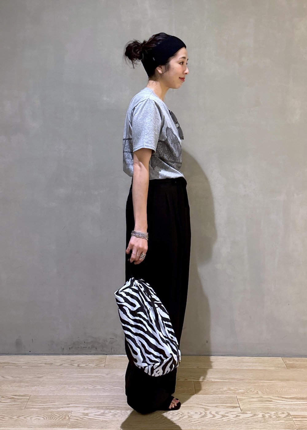 グレー系のTシャツ/カットソー、ブラック系のスラックス、ホワイト系のネックレスを着用したレディースの夏コーディネートの3枚目の写真