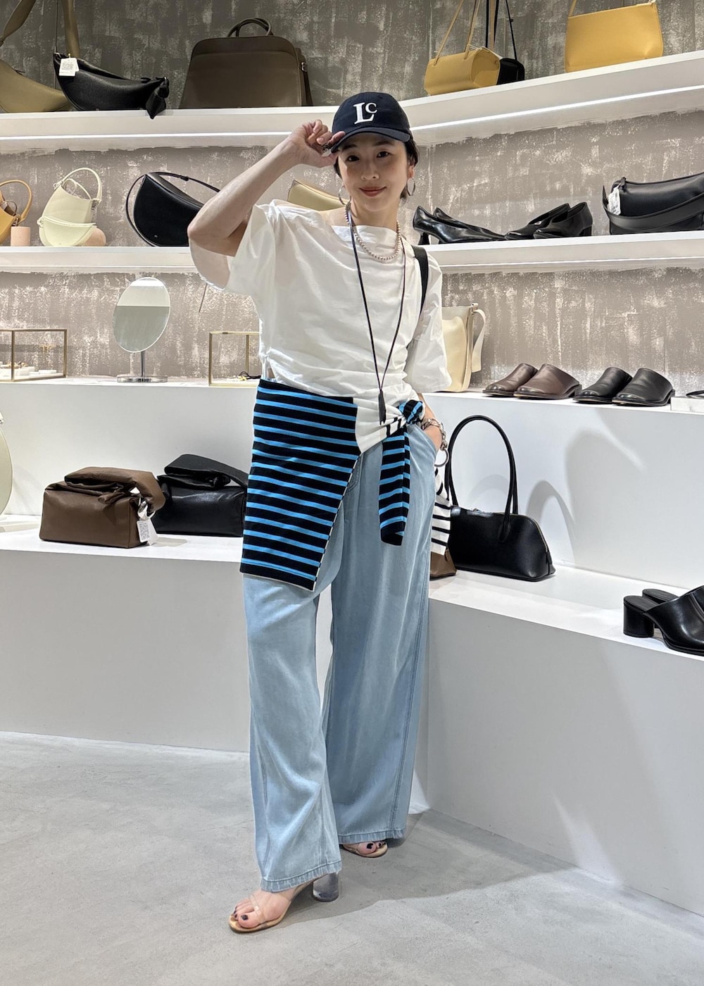 ブルー系のデニムパンツ、ブラック系のショルダーバッグ、ブルー系のTシャツ/カットソーを着用したレディースの春コーディネートの2枚目の写真