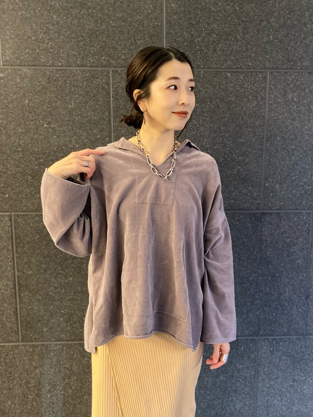 グレー系のパーカー、ベージュ系のスカート、シルバー系のネックレスを着用したレディースの春コーディネートの2枚目の写真