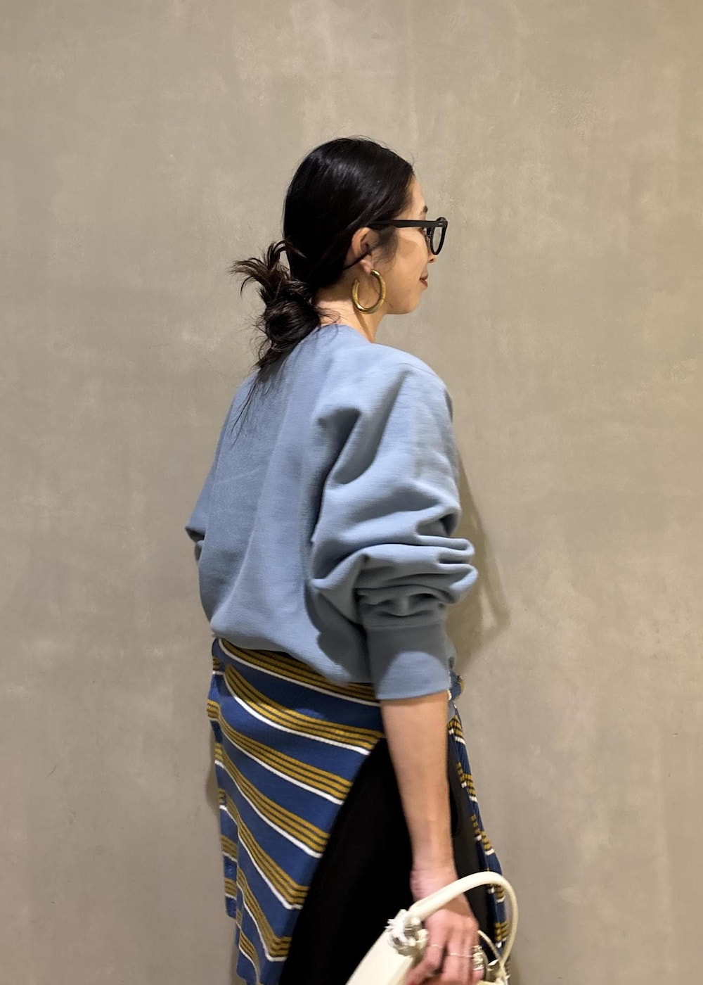 ホワイト系のハンドバッグ、ブルー系のスウェット、ブルー系のポロシャツを着用したレディースの秋コーディネートの7枚目の写真