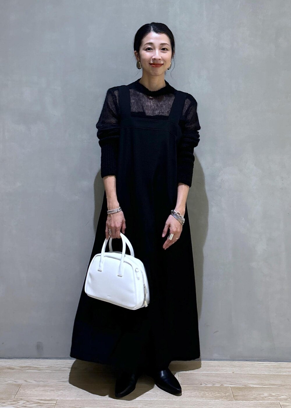ホワイト系のボストンバッグ、ブラック系のワンピース、ブラック系のブーツを着用したレディースの秋コーディネートの2枚目の写真