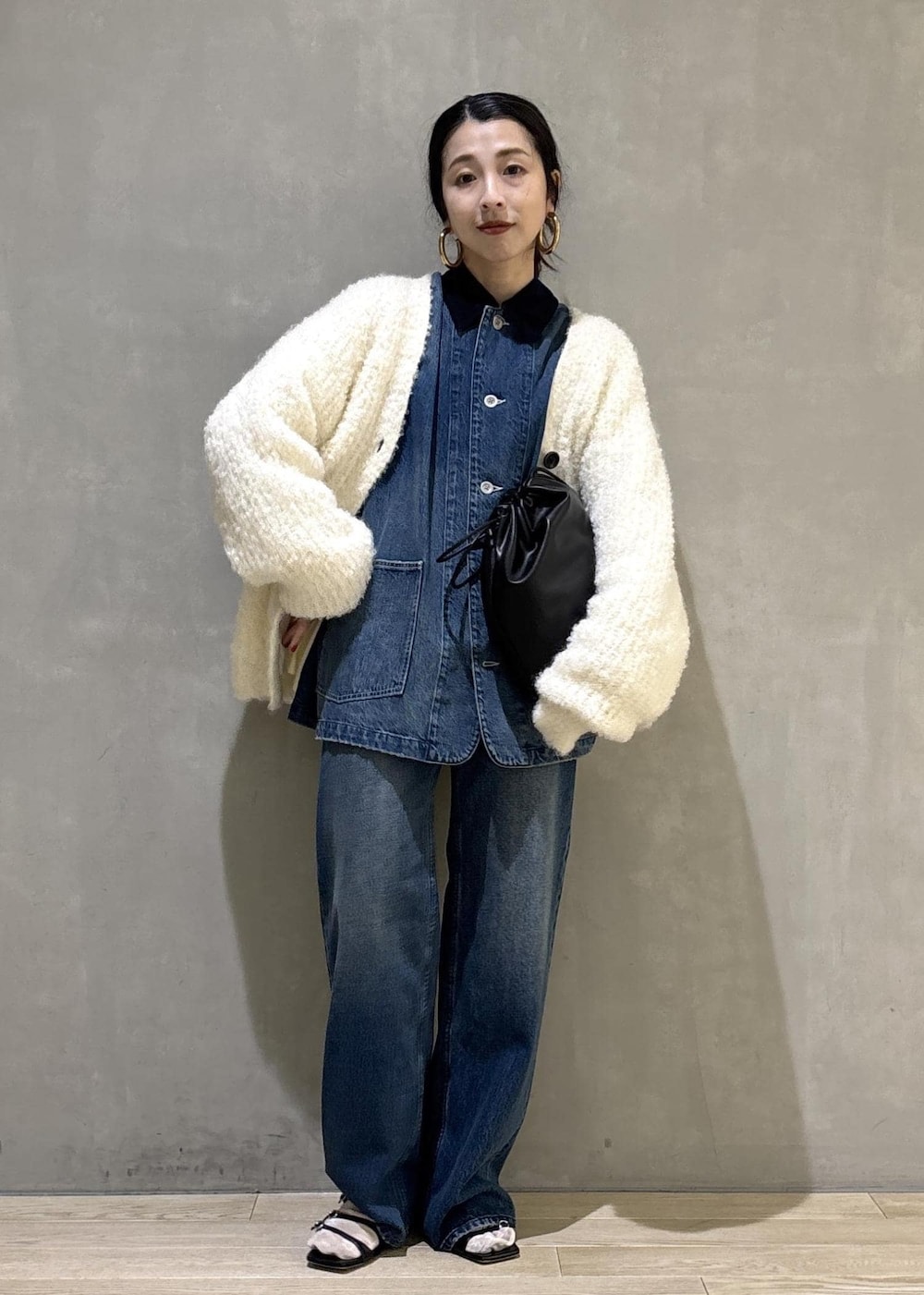 ブラック系のショルダーバッグ、ブルー系のデニムパンツ、ブルー系のカバーオールを着用したレディースの秋コーディネートの3枚目の写真