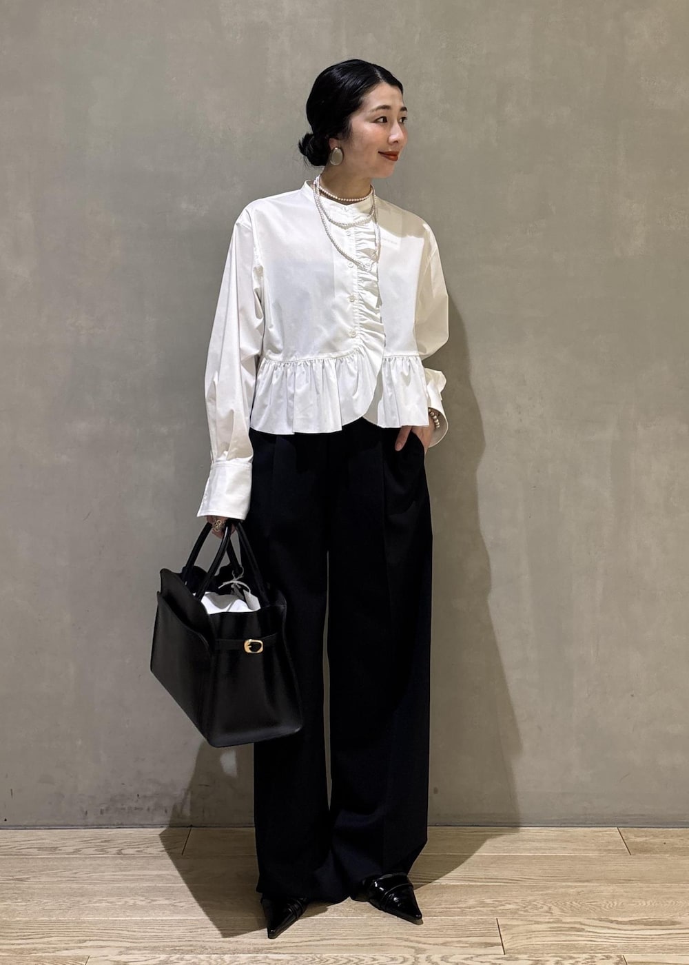 ホワイト系のシャツ/ブラウス、ブラック系のスラックス、ブラック系のトートバッグを着用したレディースの冬コーディネートの4枚目の写真