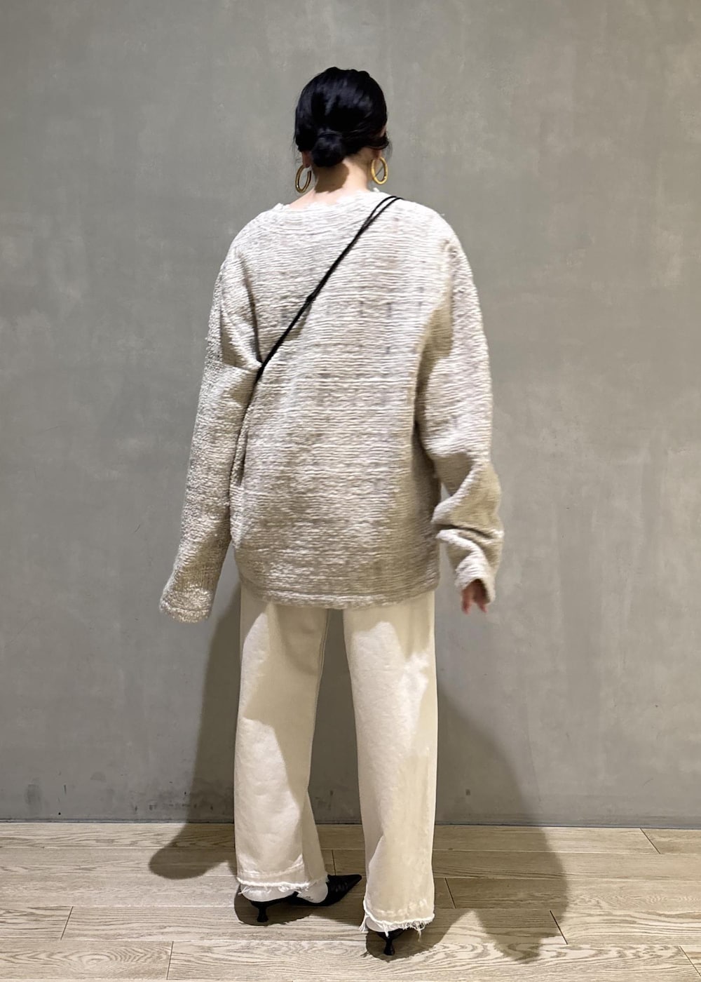 ブラック系のサンダル、ホワイト系のデニムパンツ、ブラック系のショルダーバッグを着用したレディースの冬コーディネートの4枚目の写真