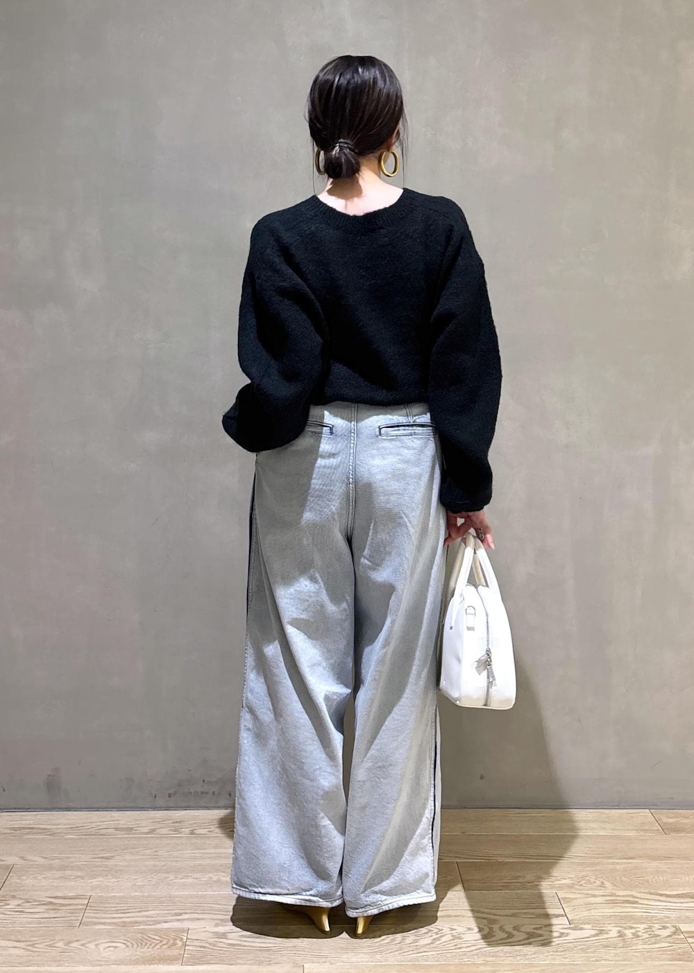 ブラック系のニット/セーター、ホワイト系のボストンバッグ、ブルー系のその他パンツを着用したレディースの冬コーディネートの4枚目の写真