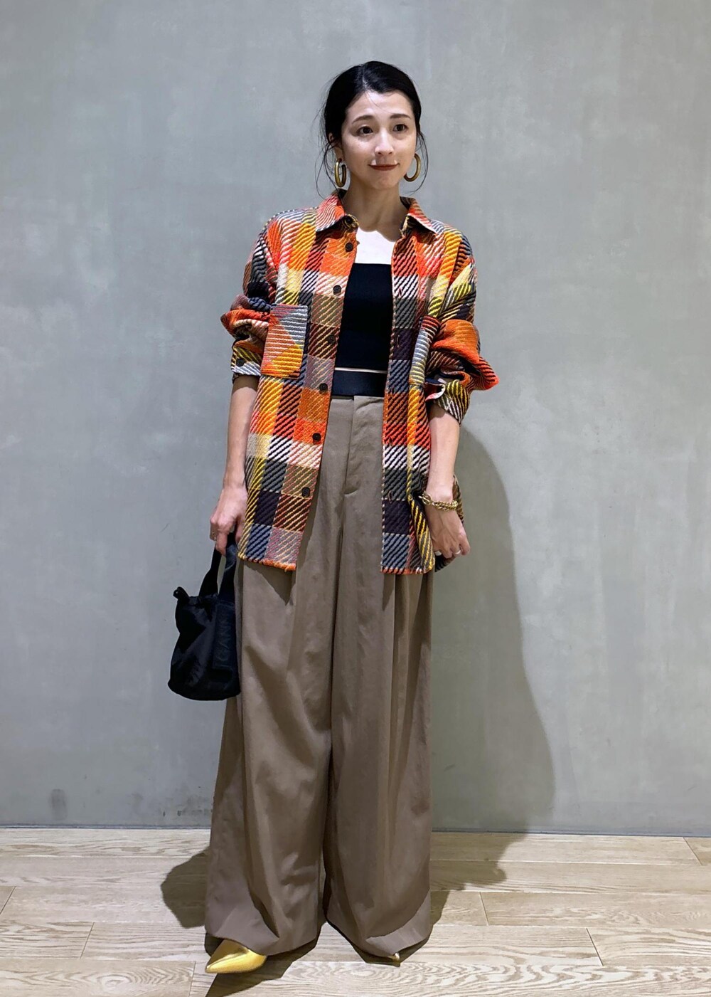 ブラック系のハンドバッグ、グリーン系のスラックスを着用したレディースの秋コーディネートの2枚目の写真