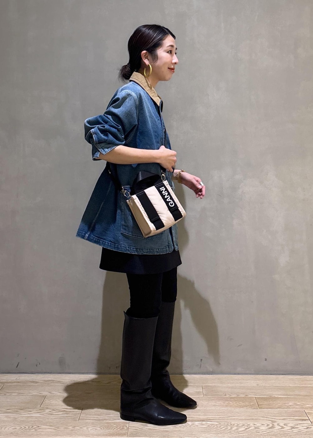 ベージュ系のトートバッグ、ブラック系のブーツ、ブラック系のスカートを着用したレディースの冬コーディネートの3枚目の写真