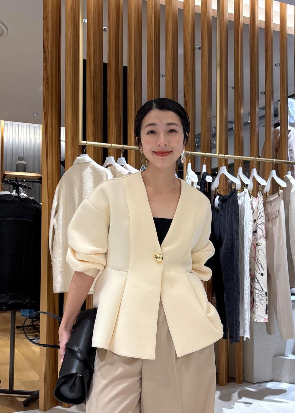 ブラック系のショルダーバッグ、ホワイト系のパンプス、ベージュ系のスラックスを着用したレディースの冬コーディネートの6枚目の写真