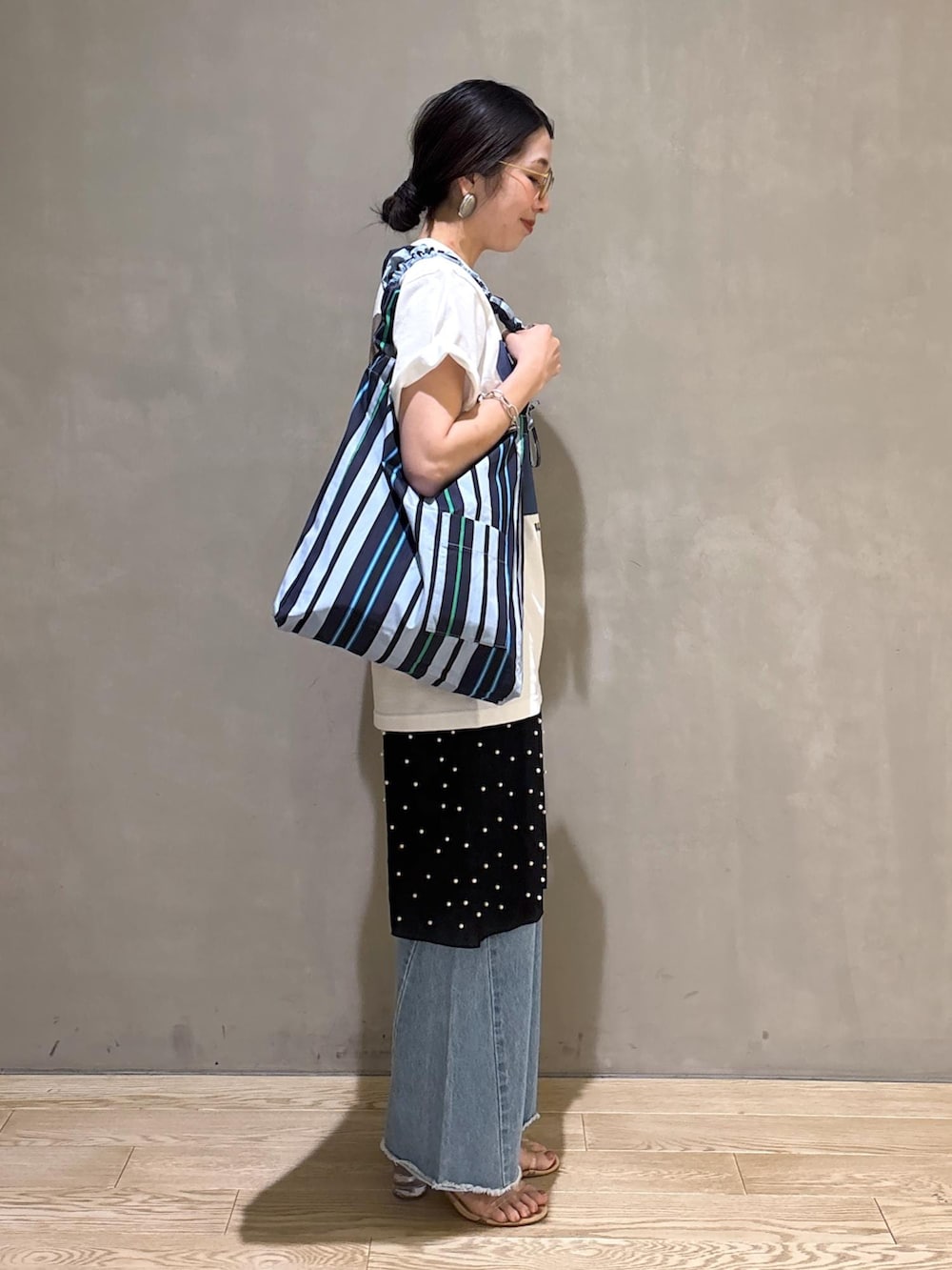 ブルー系のデニムパンツ、ブルー系のショルダーバッグ、ホワイト系のTシャツ/カットソーを着用したレディースの春コーディネートの5枚目の写真