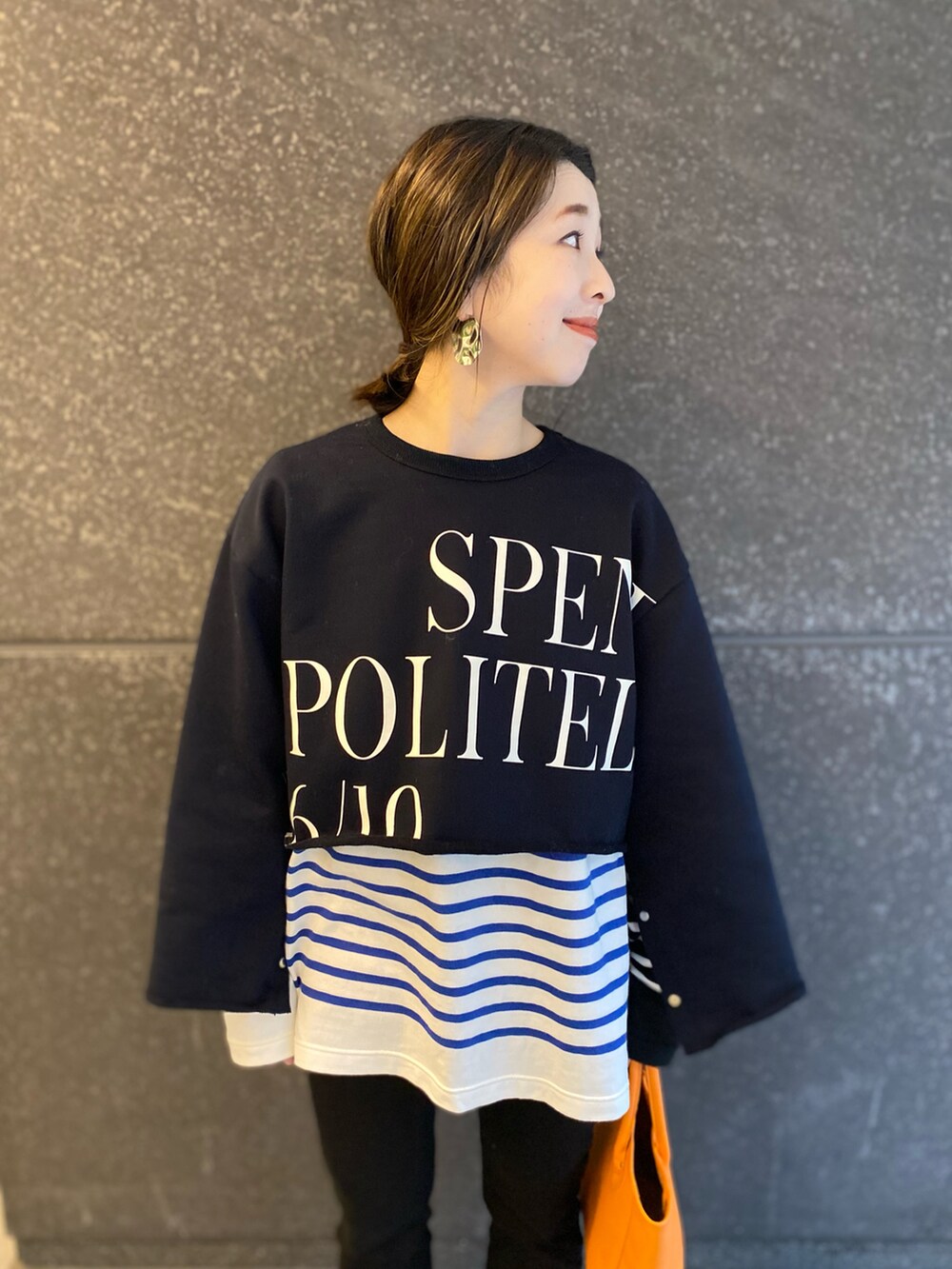 ブラック系のデニムパンツ、オレンジ系のトートバッグ、ブルー系のスウェットを着用したレディースの春コーディネートの2枚目の写真