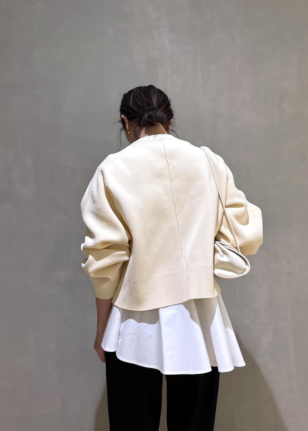 ホワイト系のパンプス、ブラック系のスラックス、ホワイト系のショルダーバッグを着用したレディースの冬コーディネートの10枚目の写真