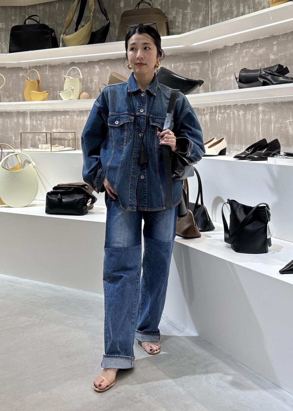 ブルー系のデニムジャケット、ブラック系のショルダーバッグ、ブルー系のデニムパンツを着用したレディースの春コーディネートの6枚目の写真