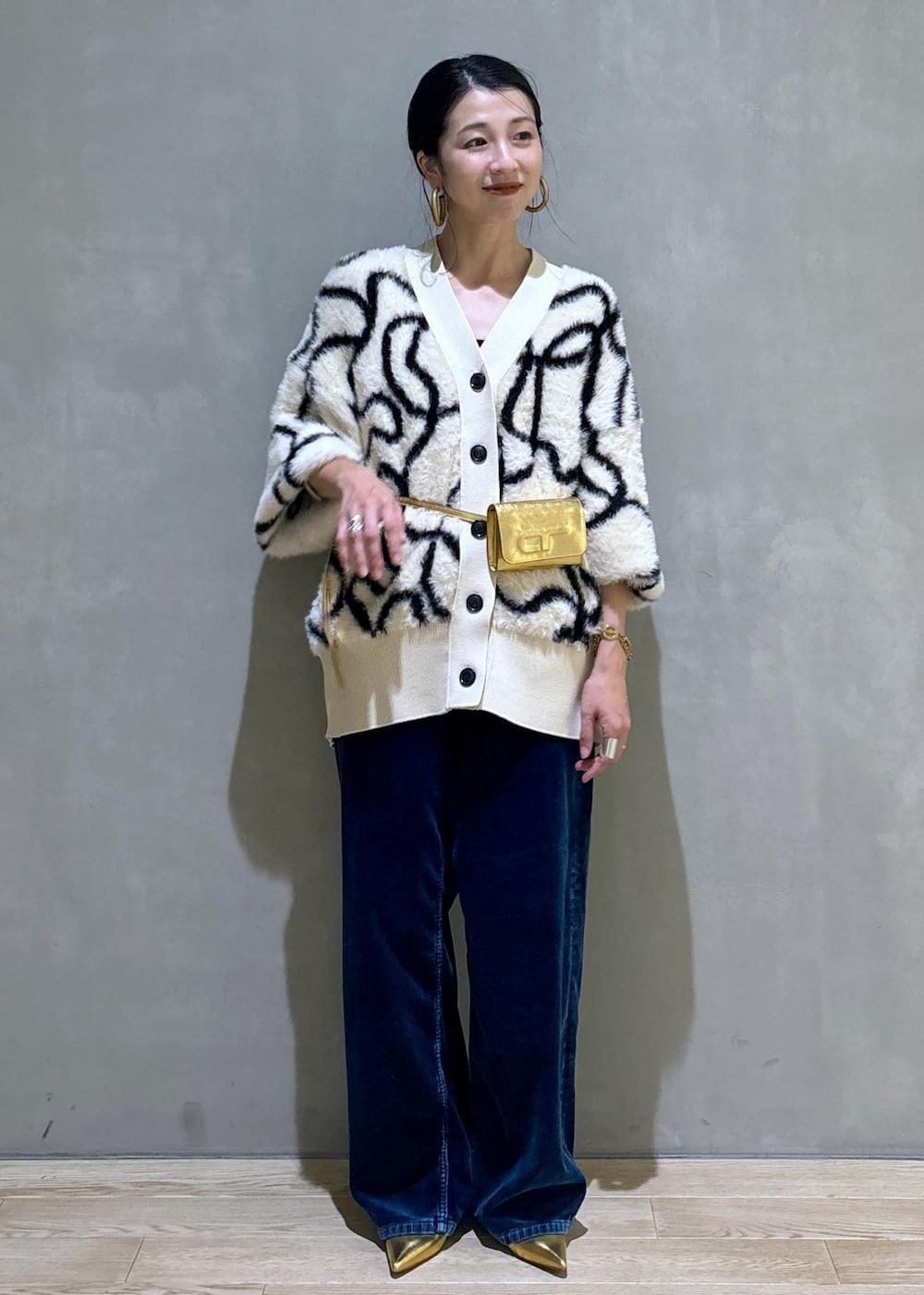 ゴールド系のその他シューズ、ゴールド系のショルダーバッグ、ホワイト系のカーディガン/ボレロを着用したレディースの秋コーディネートの2枚目の写真