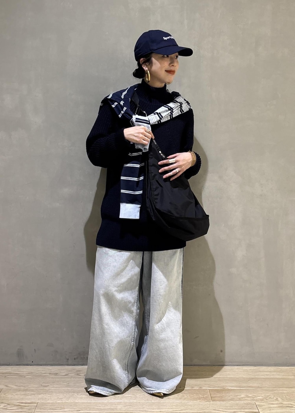 ブルー系のデニムパンツ、ブラック系のショルダーバッグを着用したレディースの秋コーディネートの2枚目の写真