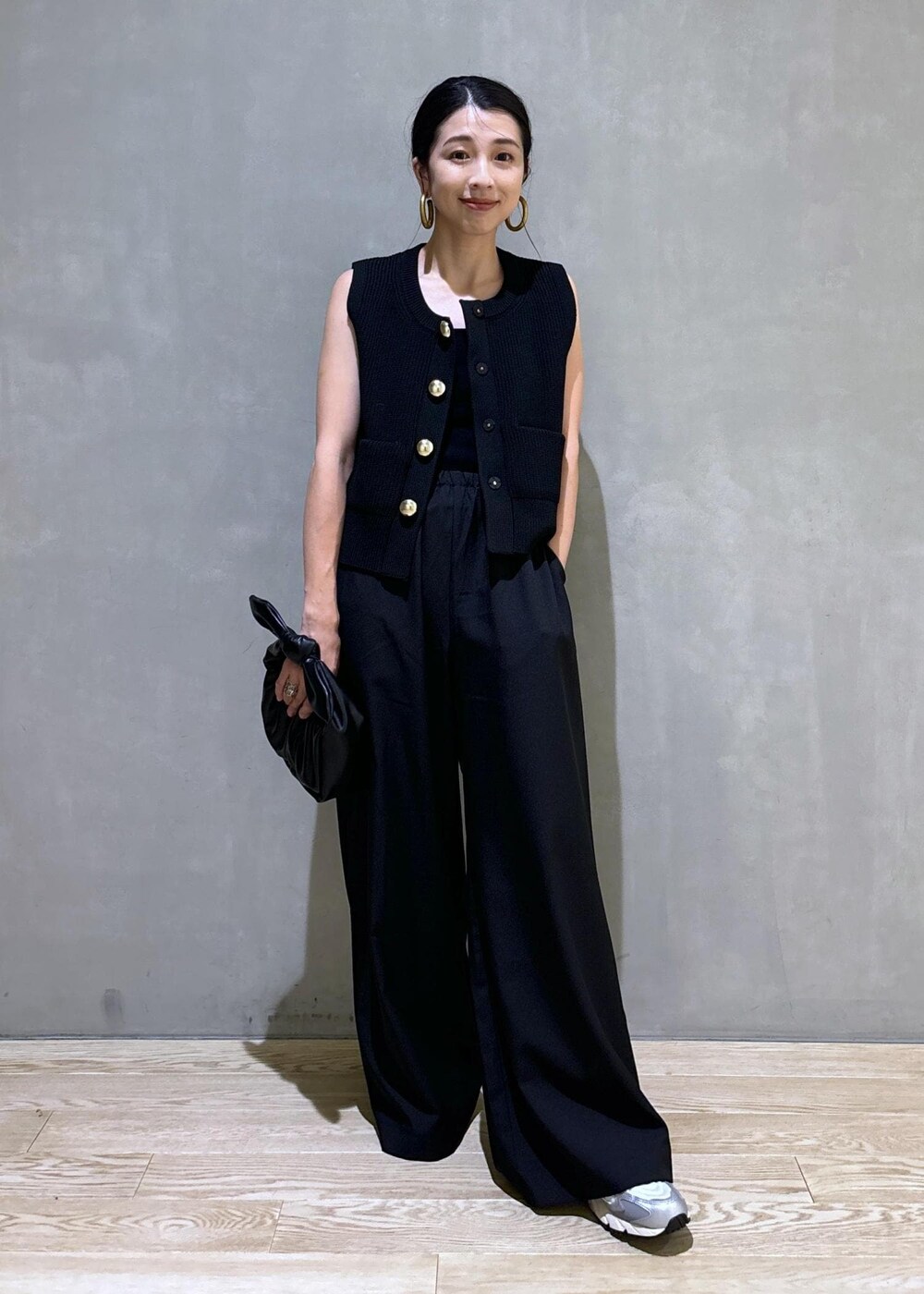 シルバー系のスニーカー、ブラック系のニット/セーター、ブラック系のショルダーバッグを着用したレディースの夏コーディネートの3枚目の写真