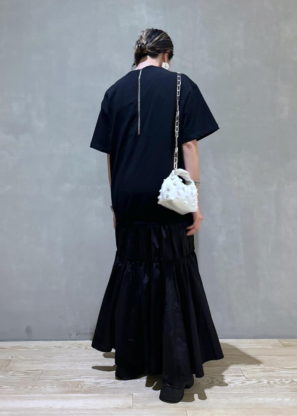 ホワイト系のショルダーバッグ、ブラック系のブーツ、ブラック系のワンピースを着用したレディースの夏コーディネートの7枚目の写真