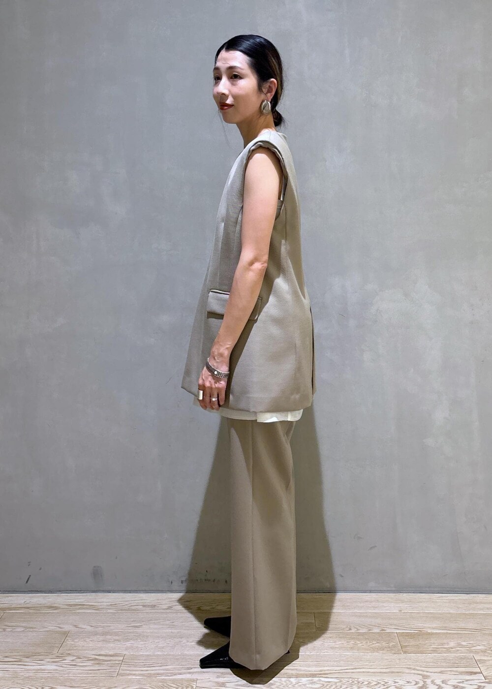 ブラック系のパンプス、ベージュ系のベスト、ベージュ系のスラックスを着用したレディースの夏コーディネートの7枚目の写真