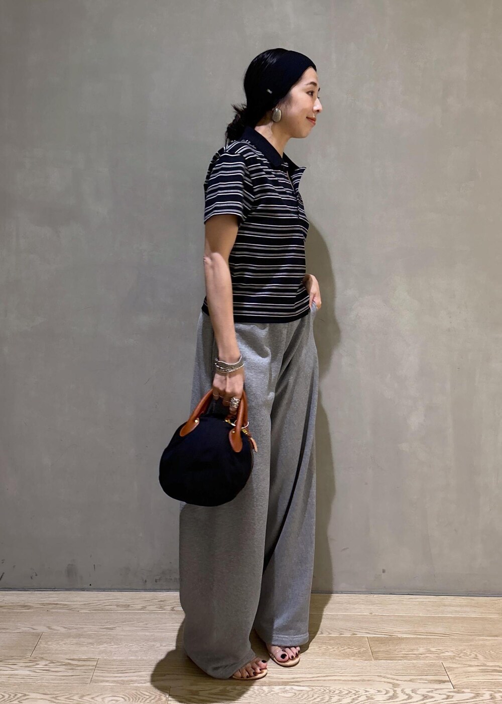 グレー系のスウェットパンツ、ブラック系のポロシャツを着用したレディースの夏コーディネートの5枚目の写真