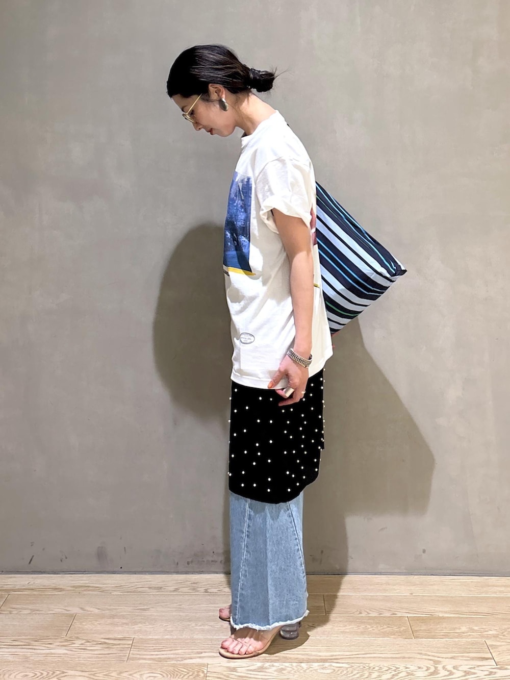 ブルー系のデニムパンツ、ブルー系のショルダーバッグ、ホワイト系のTシャツ/カットソーを着用したレディースの春コーディネートの8枚目の写真