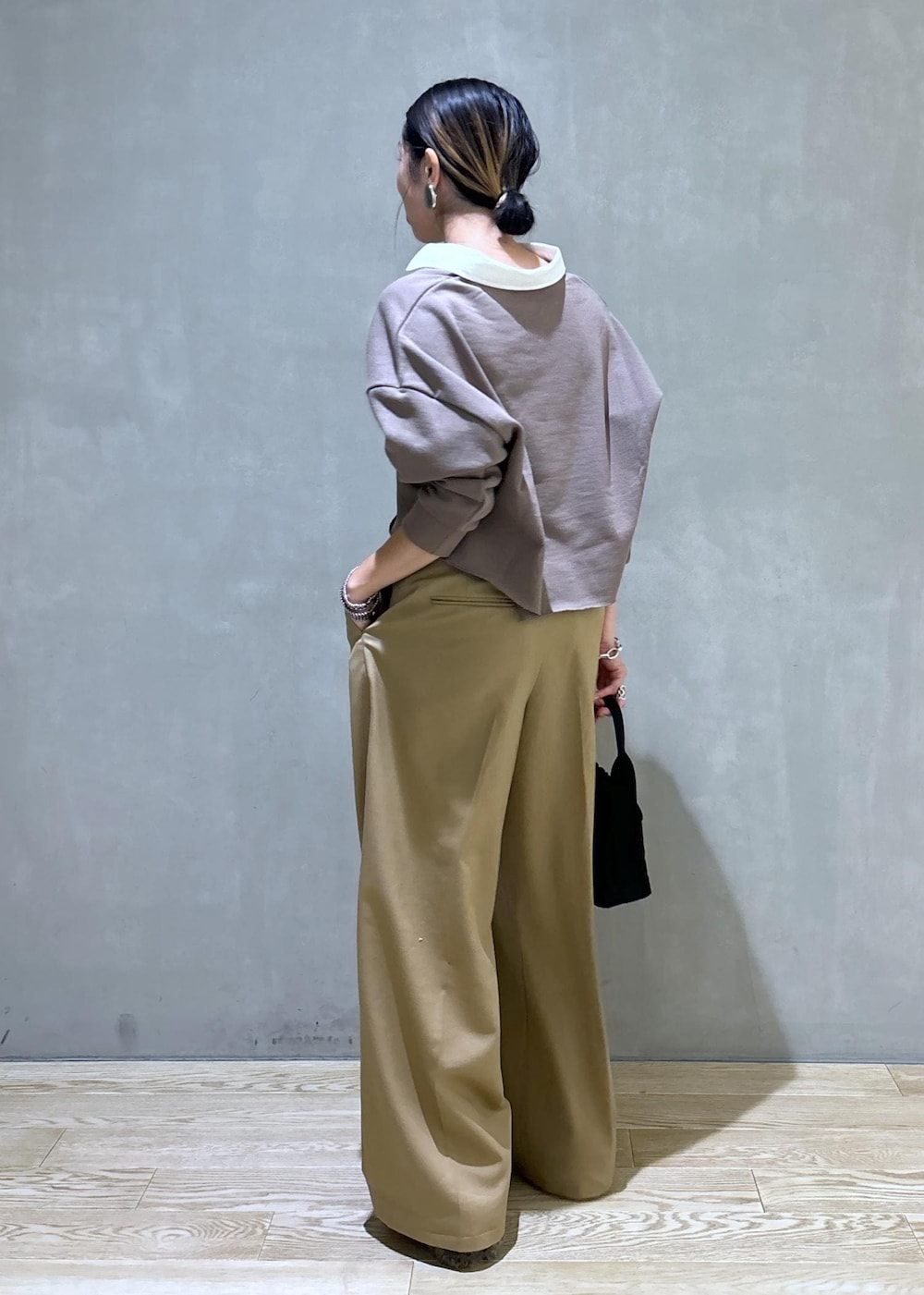 ブラック系のハンドバッグ、ブラウン系のサンダル、ベージュ系のTシャツ/カットソーを着用したレディースの秋コーディネートの4枚目の写真