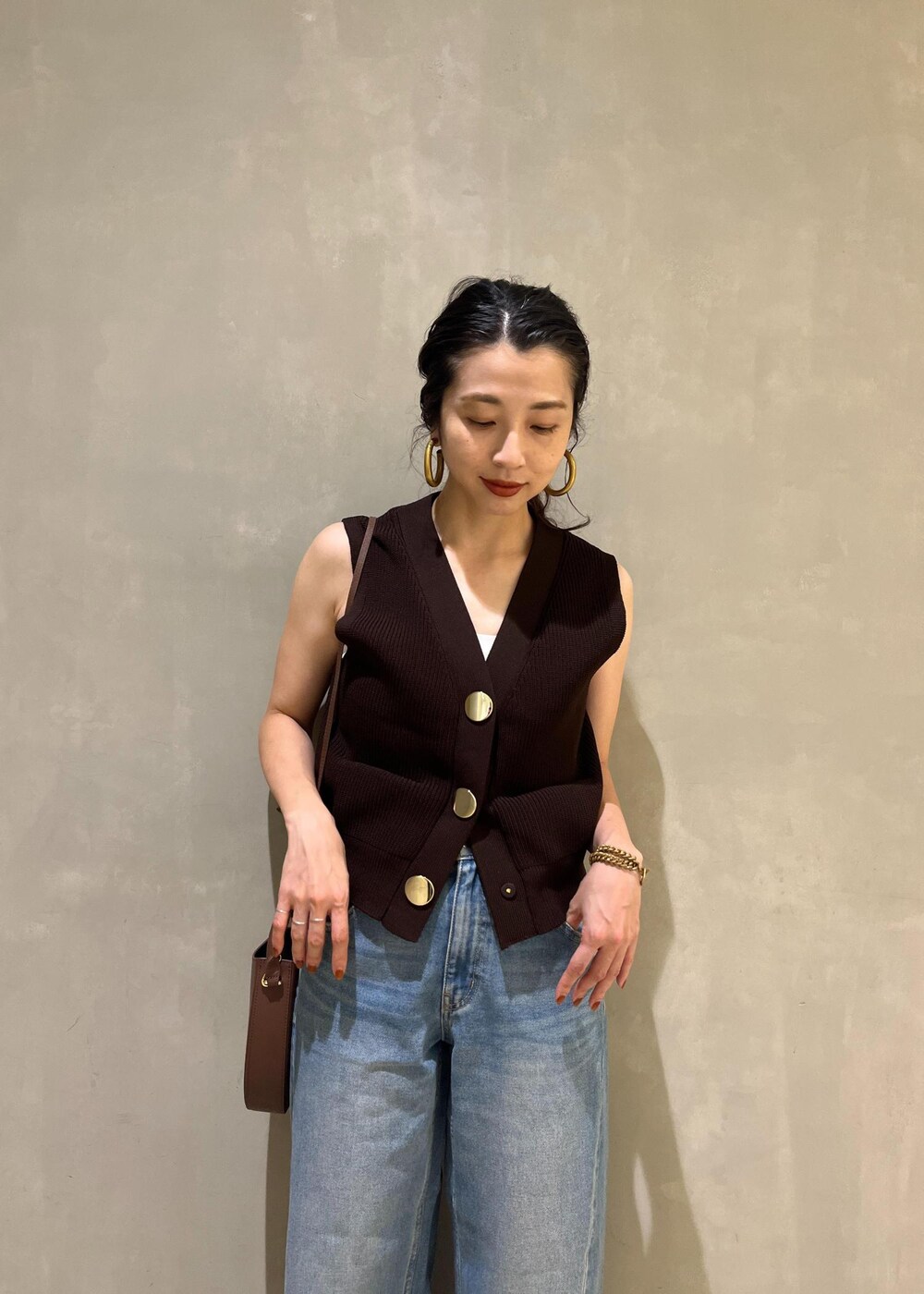 ブルー系のデニムパンツ、ブラウン系のサンダル、ブラウン系のベストを着用したレディースの夏コーディネートの10枚目の写真