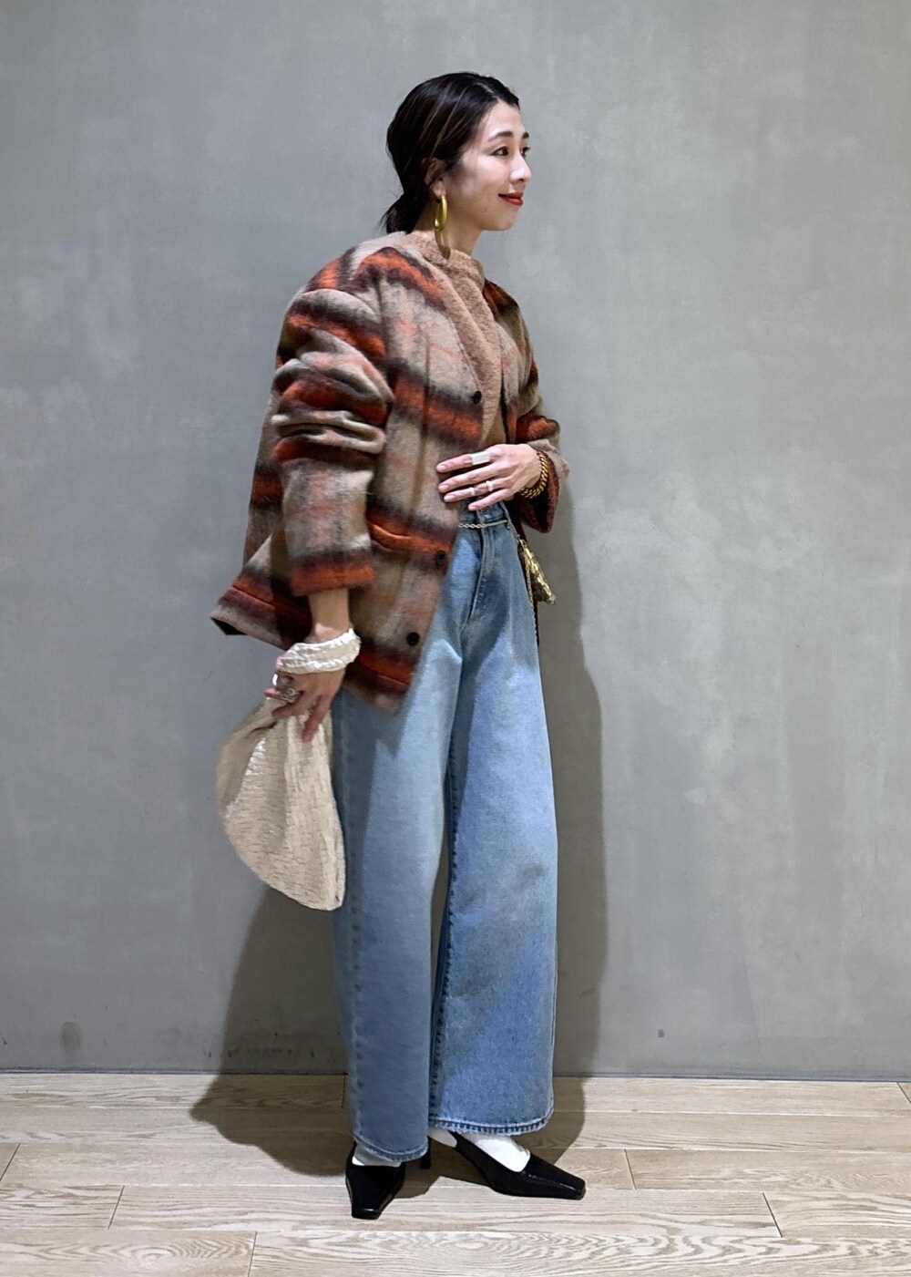 ホワイト系のハンドバッグ、ゴールド系のショルダーバッグ、ブルー系のデニムパンツを着用したレディースの冬コーディネートの7枚目の写真