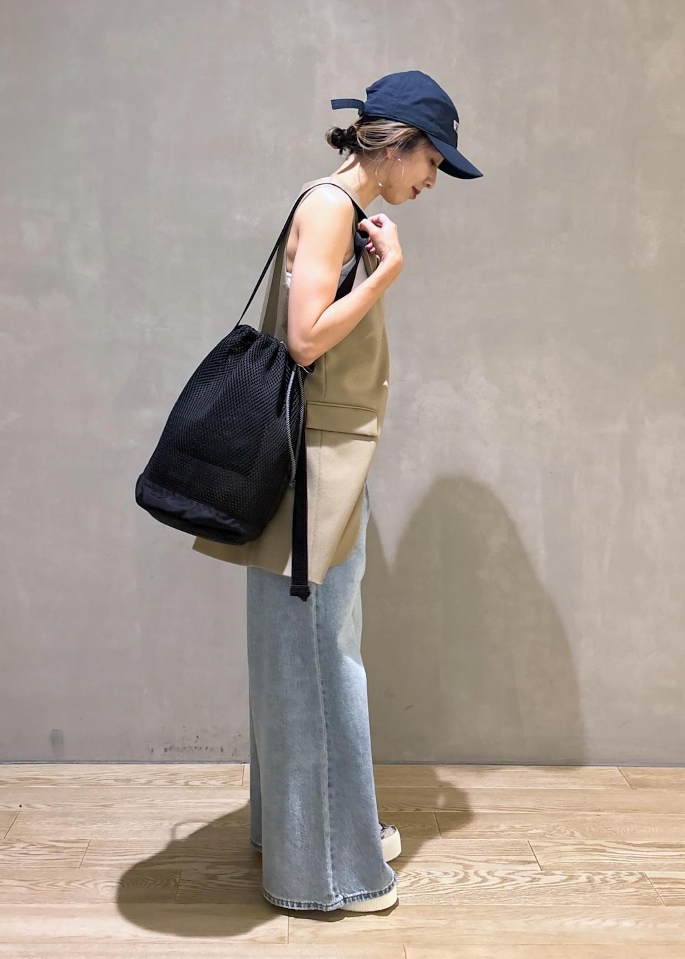 ベージュ系のベスト、ブラック系のスニーカー、ブラック系のショルダーバッグを着用したレディースの夏コーディネートの5枚目の写真