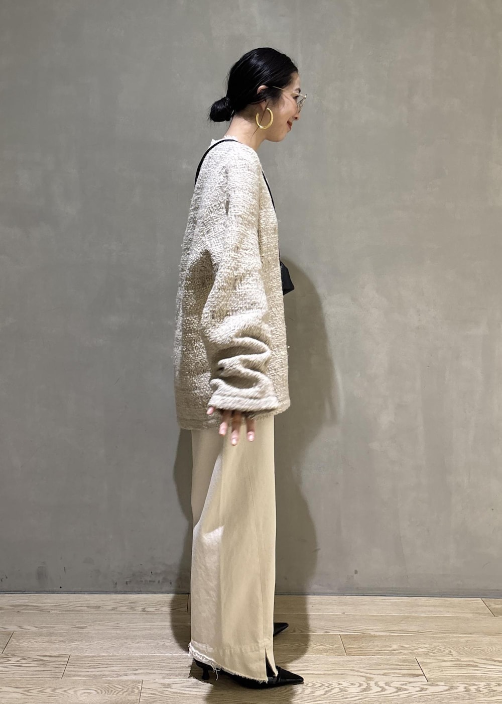 ブラック系のサンダル、ホワイト系のデニムパンツ、ブラック系のショルダーバッグを着用したレディースの冬コーディネートの3枚目の写真