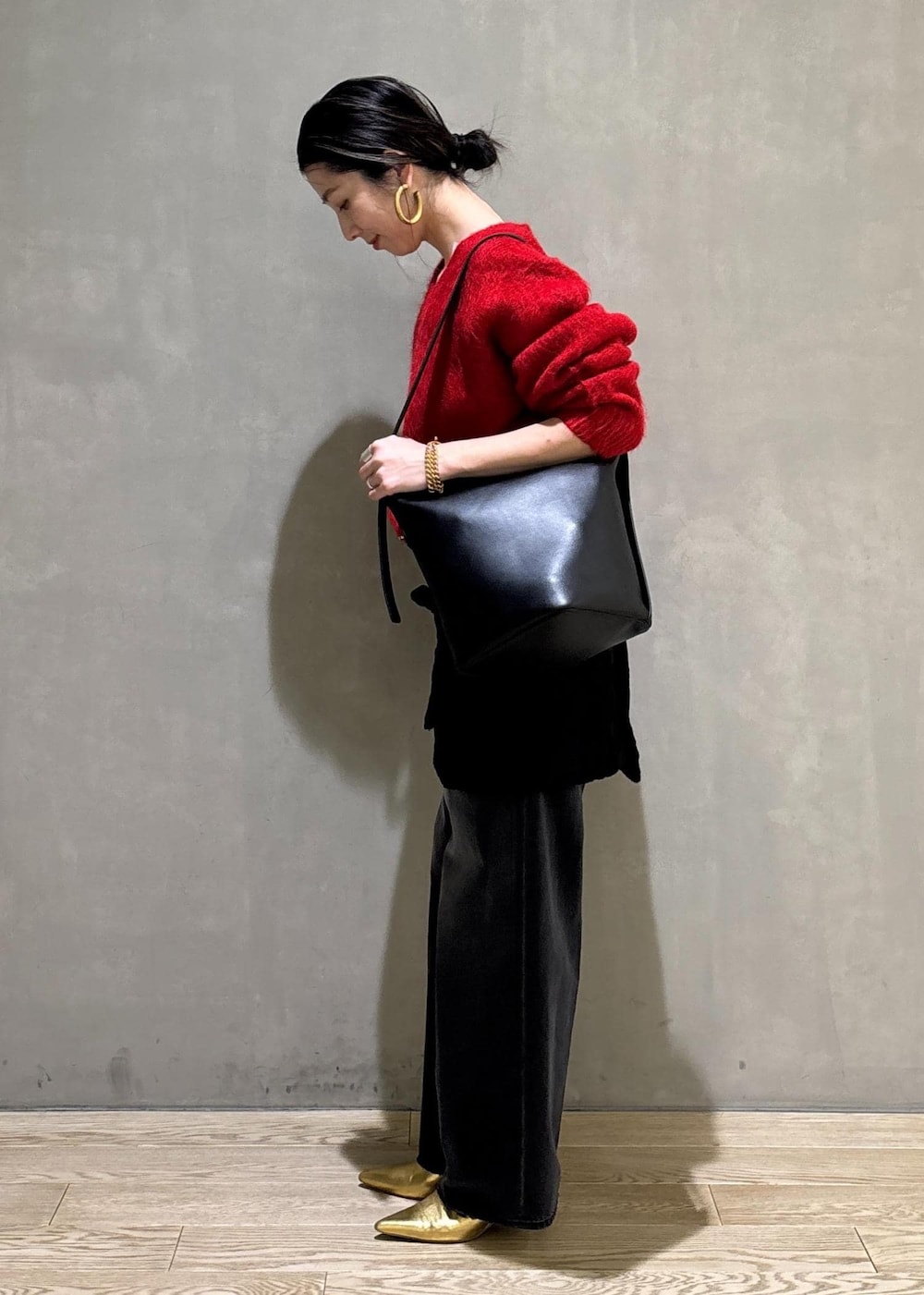 レッド系のニット/セーター、ブラック系のスカート、ブラック系のデニムパンツを着用したレディースの冬コーディネートの7枚目の写真